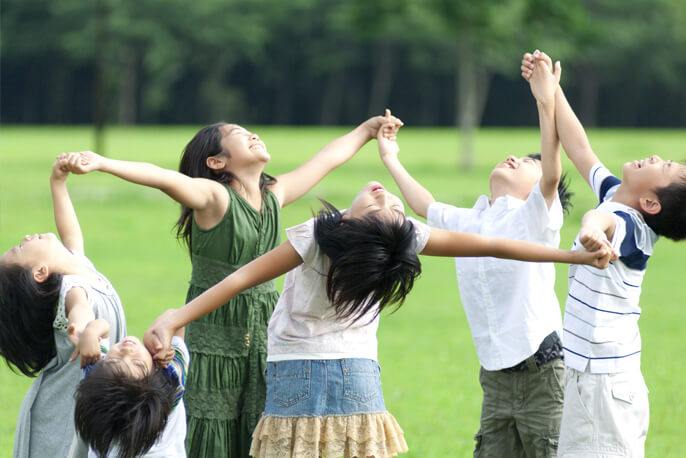 手を繋ぎ輪になって笑う6人の小学生