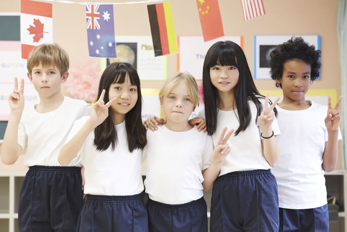 肩を組んでピースをする国籍の異なる5人の子供