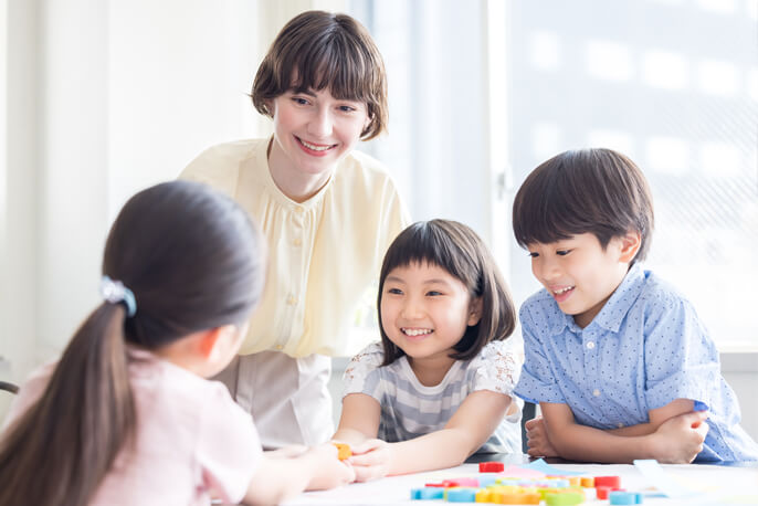 外国人教師と楽しそうに学ぶ3人の子供