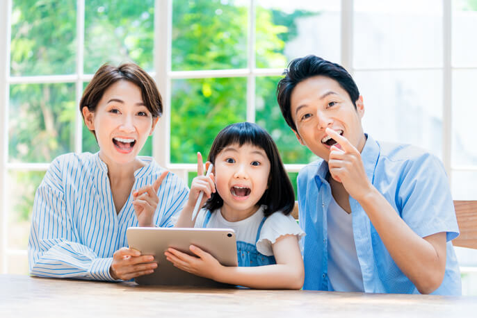 タブレットを持ち指差しをする女の子と母と父