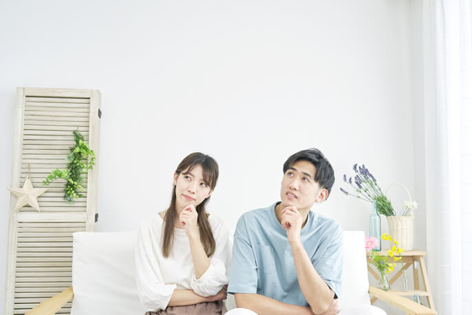 腕を組み首を傾げる夫婦