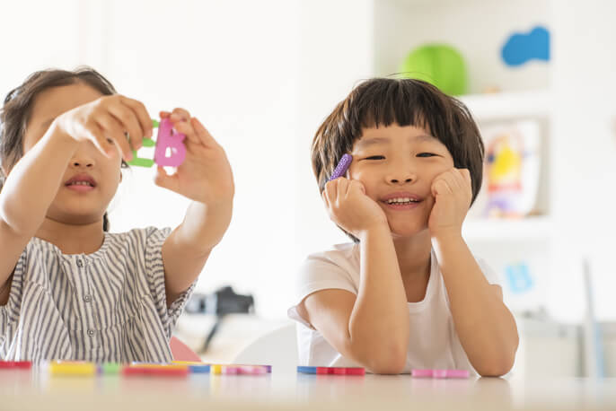 アルファベットのおもちゃを手に持つ2人の子供