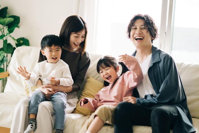 ソファーに座って笑う4人家族