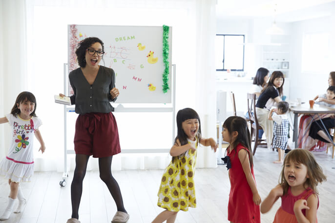 学童内で笑いながら走り回る子供と先生