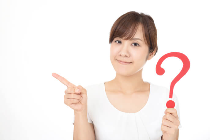 クエスチョンマークを持って指差しをする女性