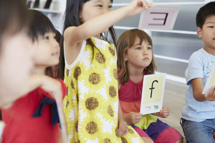 英語のカードを持って学習する子供たち