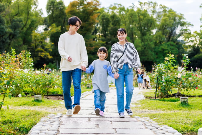 女の子を真ん中に手を繋ぐ3人家族