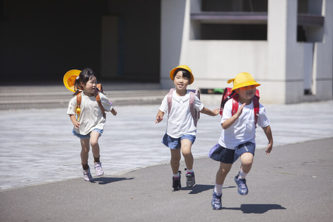 アスファルトを走り回る3人の小学生